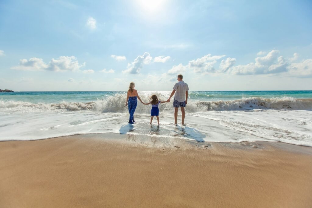 Familia con hijo caminando tomada de la mano en la playa, simbolizando protección familiar y la tranquilidad que brindan los seguros de vida.