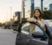 Mujer sonriente junto a su auto, protegida con seguro todo riesgo en Colombia